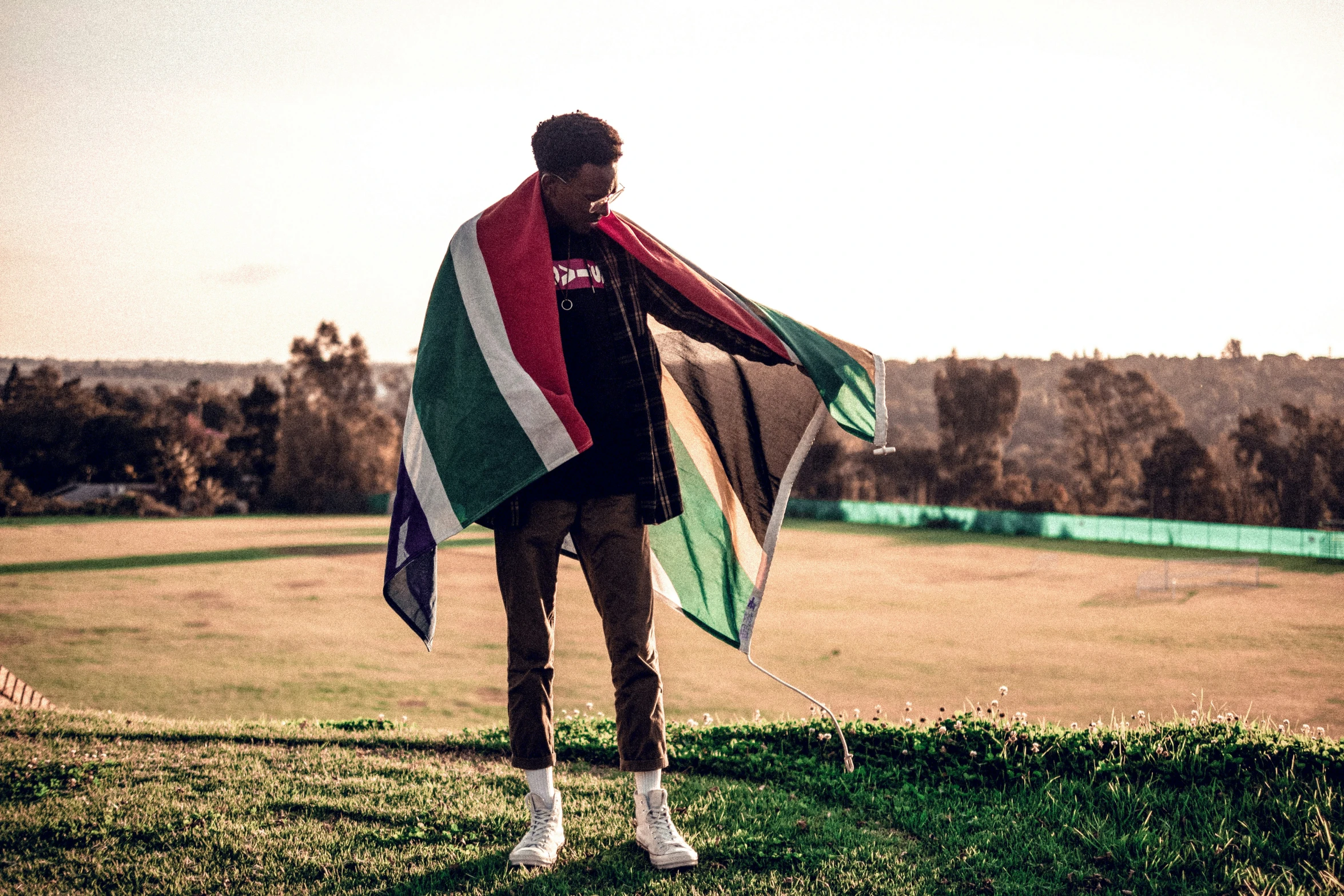 a man holding a colorful scarf standing in a field