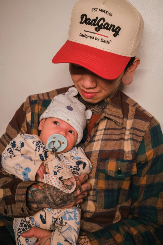 a man holds a baby and wears a hat