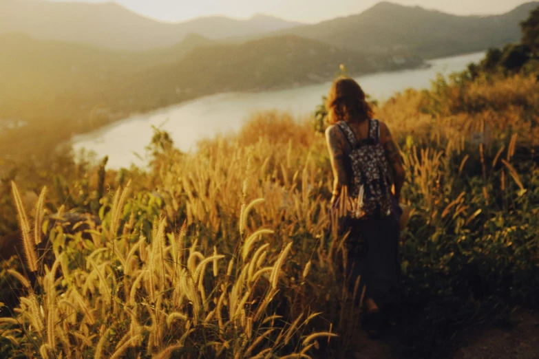 a girl standing in a field overlooking some mountains