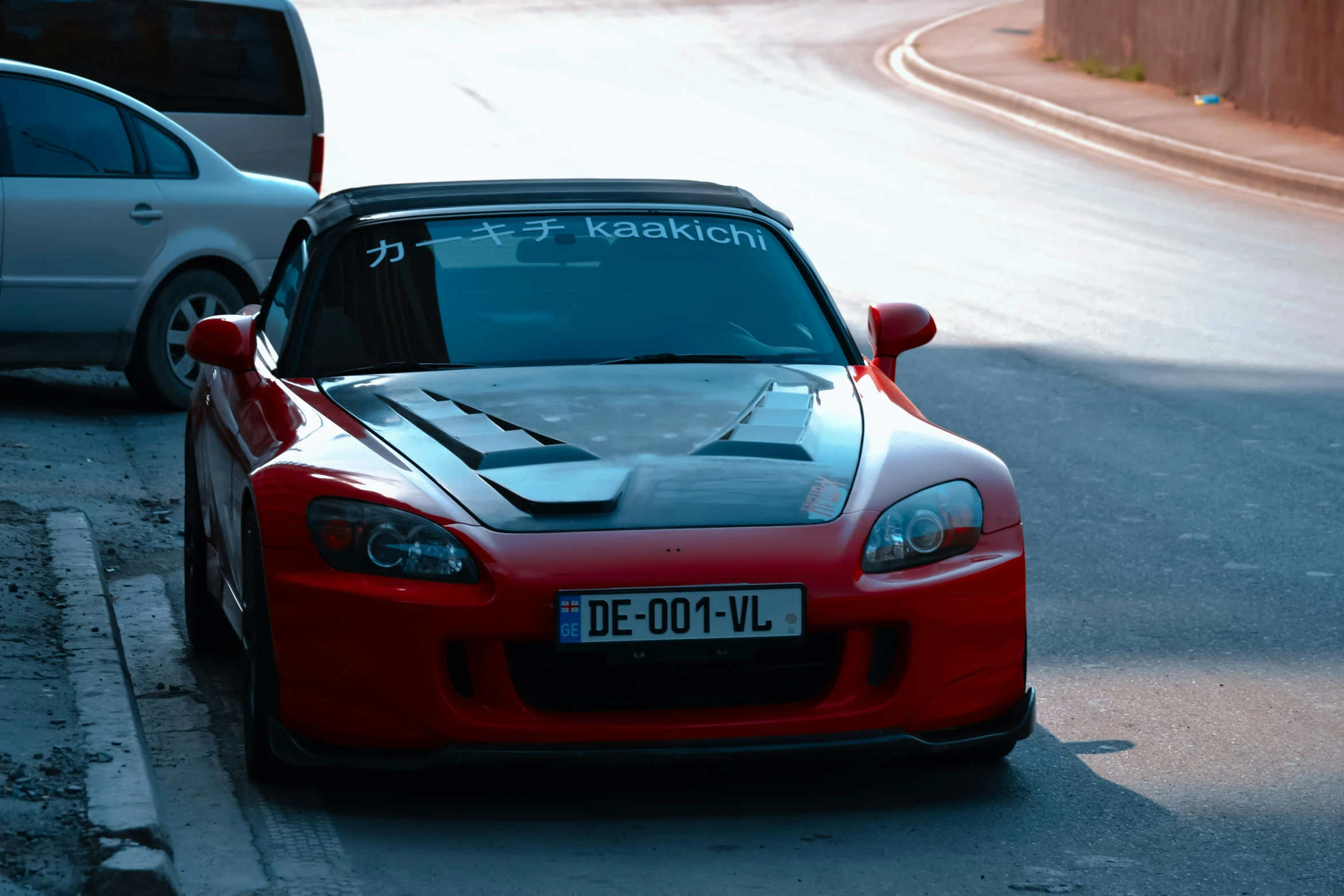 a red sports car parked next to a white car