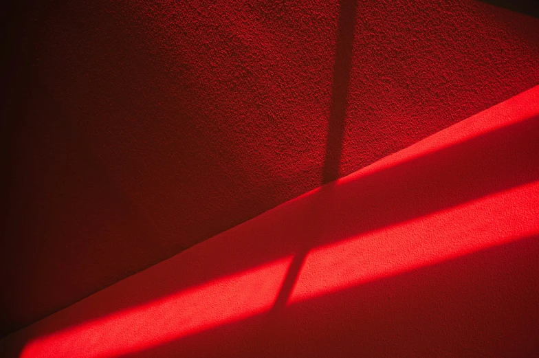 a floor lamp casting red light onto a white wall