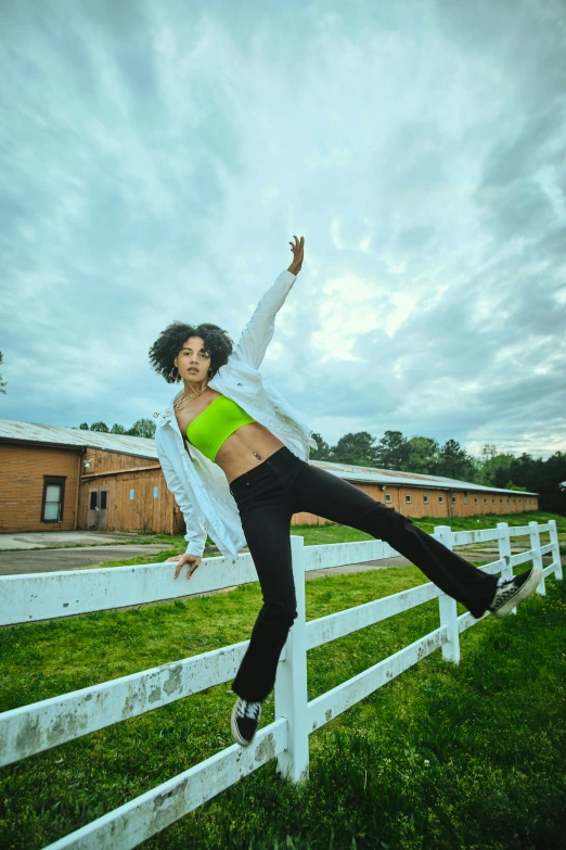 a woman in sports clothing jumping over a fence