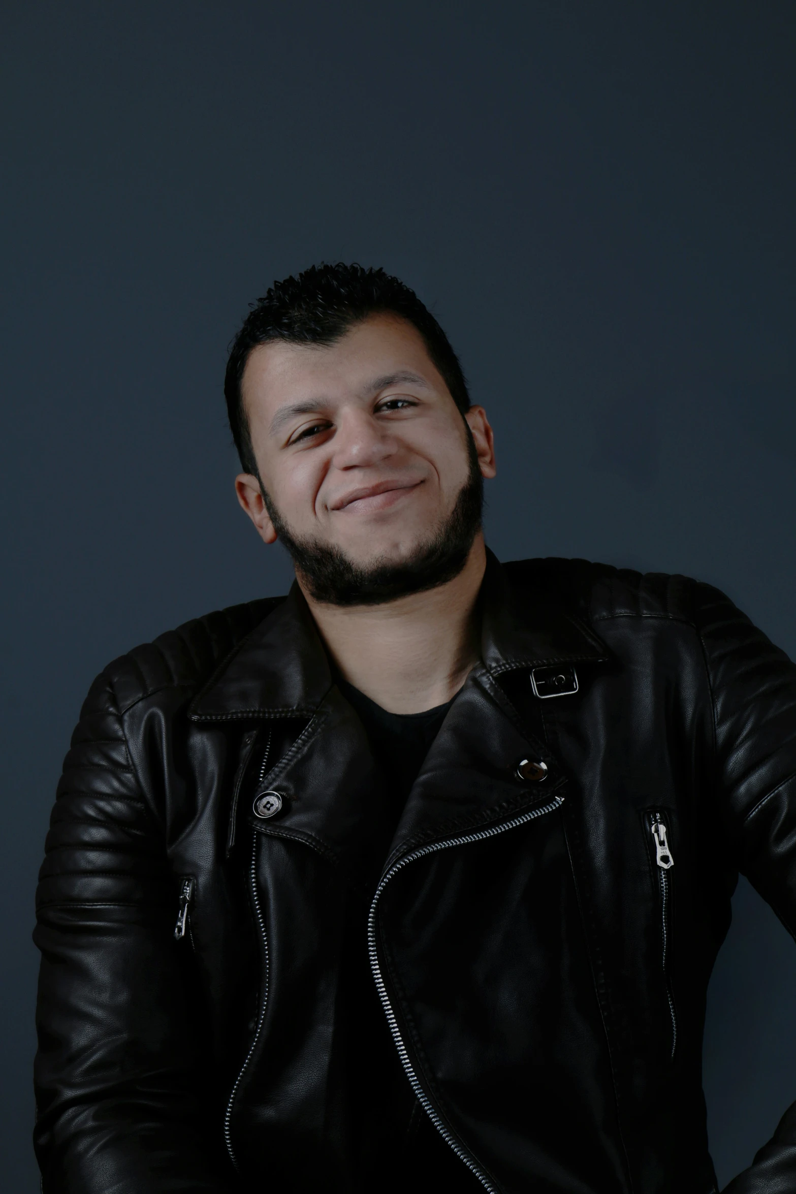 a bearded man in black jacket smiling at the camera