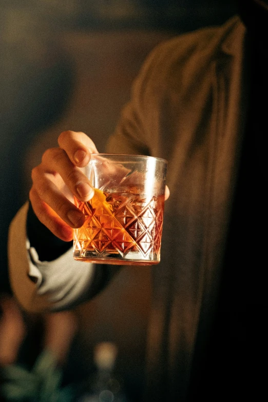 someone holding a glass of alcoholic cocktail with ice in it