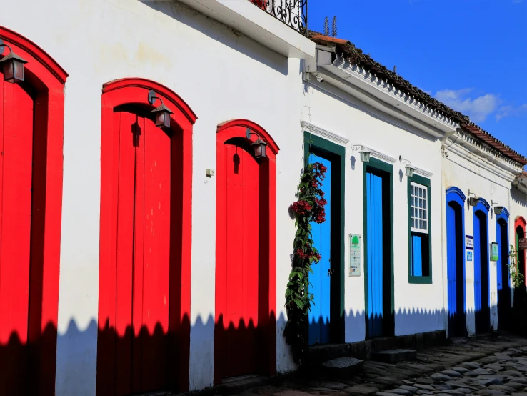 a row of white and blue buildings with red doors
