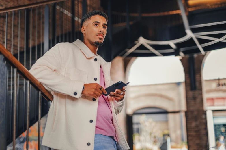 a man holding a cell phone standing under an umbrella