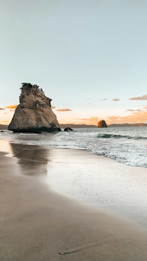 a rock out in the ocean near some sand