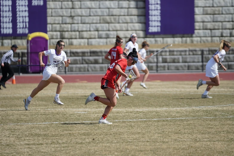 a group of girls on a field playing lacrosse