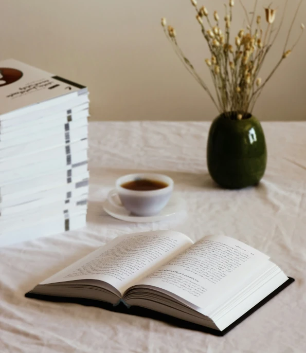 there are four books, one of which has a cup of coffee on top