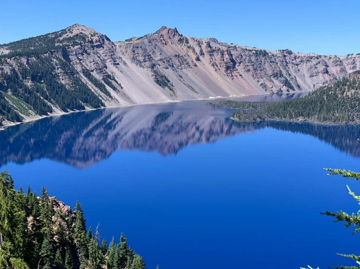 mountains and a lake surrounded by trees, on a clear day