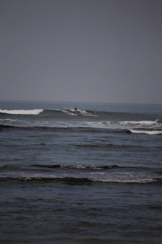 two surfers are riding a wave off the coast