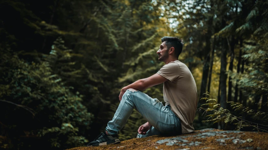 a man sitting on the rocks in the middle of the woods