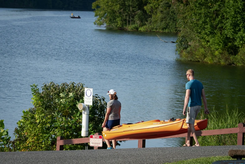 the man and woman are looking at a red canoe