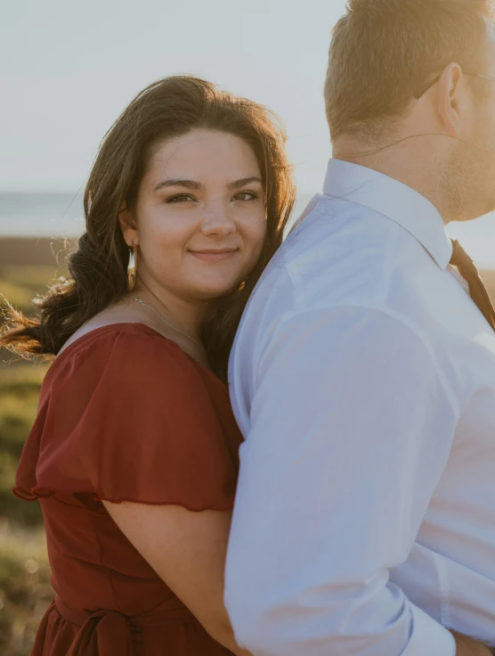 a beautiful young woman hugging a man in a field