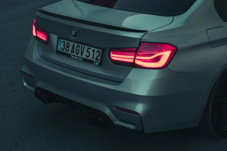 an rear end view of a silver car with lights on