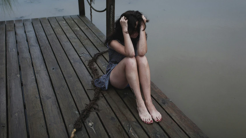 woman sitting on dock alone and sad