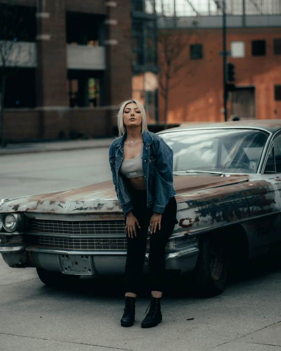 a woman leaning against an old car on the sidewalk