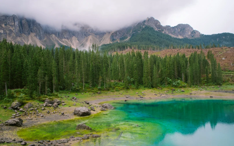 a lake sits surrounded by trees near a mountain range