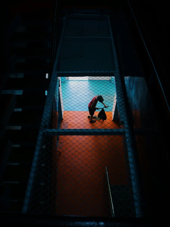 person holding umbrella up against fence near open stairway