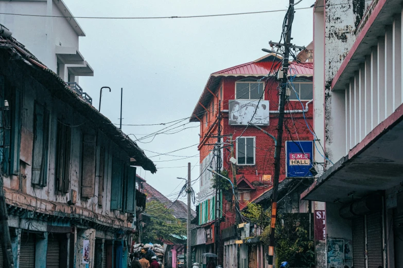 two people walk down a narrow alleyway with shops on both sides