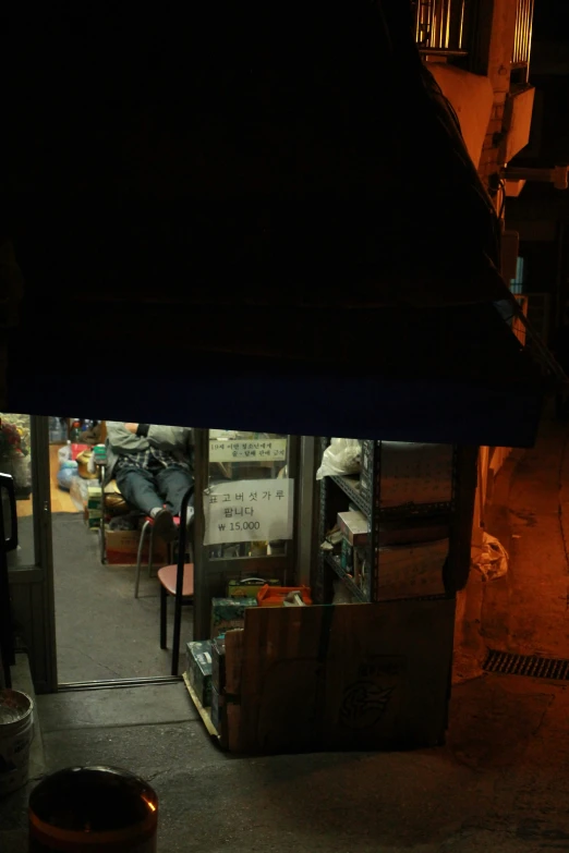 a dark picture of a storefront that has boxes and a umbrella in it