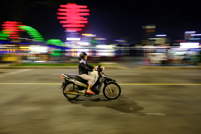 a man on a motorcycle driving down a street in the evening