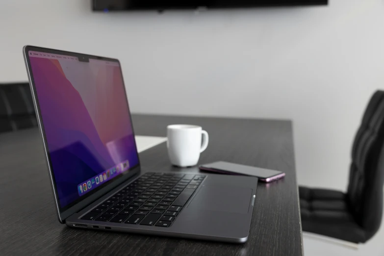 a black table with an open laptop and cell phone on it