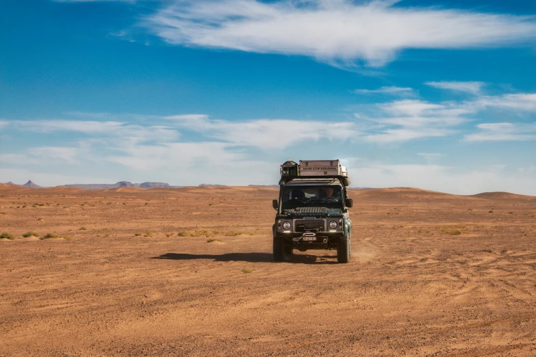 a truck in the desert driving down a dirt road