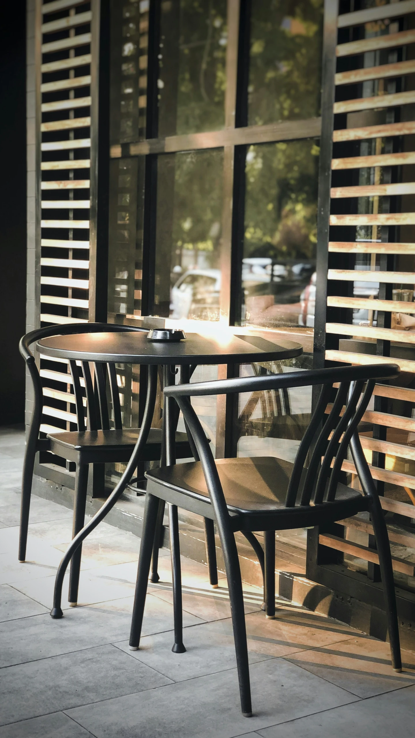 two empty chairs sit on the sidewalk next to a table