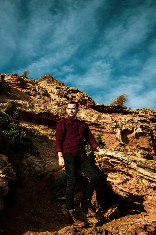 the man is standing on a cliff ledge