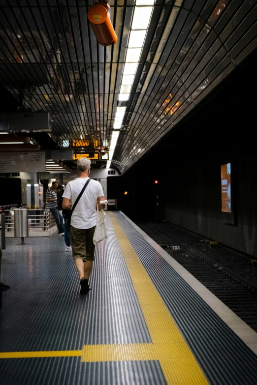 a man walking down a walkway with a bag