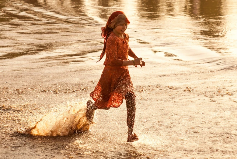 girl wearing an orange dress running through the water