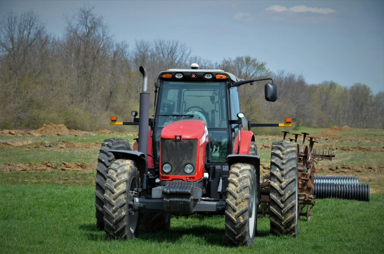 a red tractor sitting on top of a lush green field