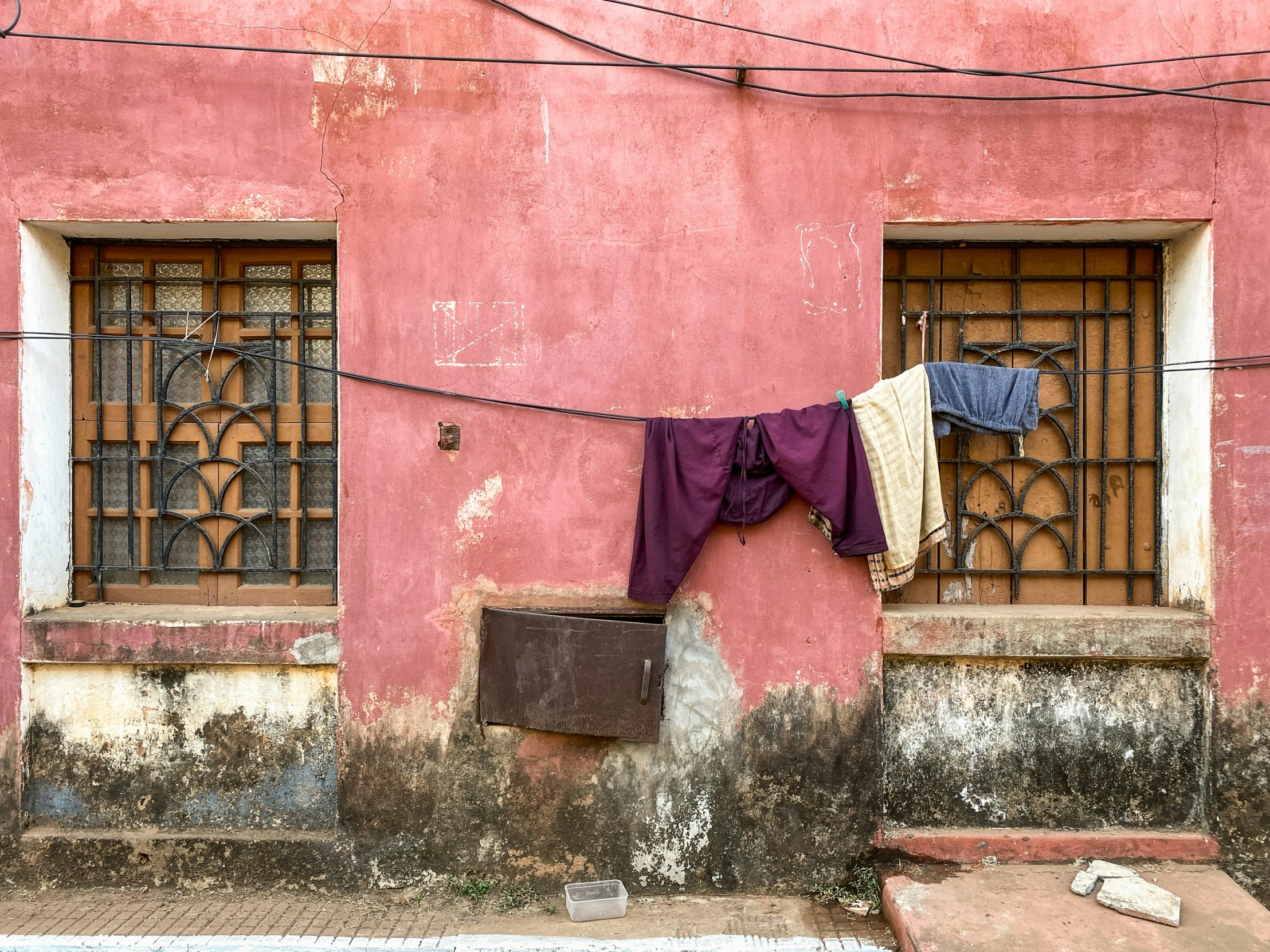 a laundry line outside a pink building with iron bars