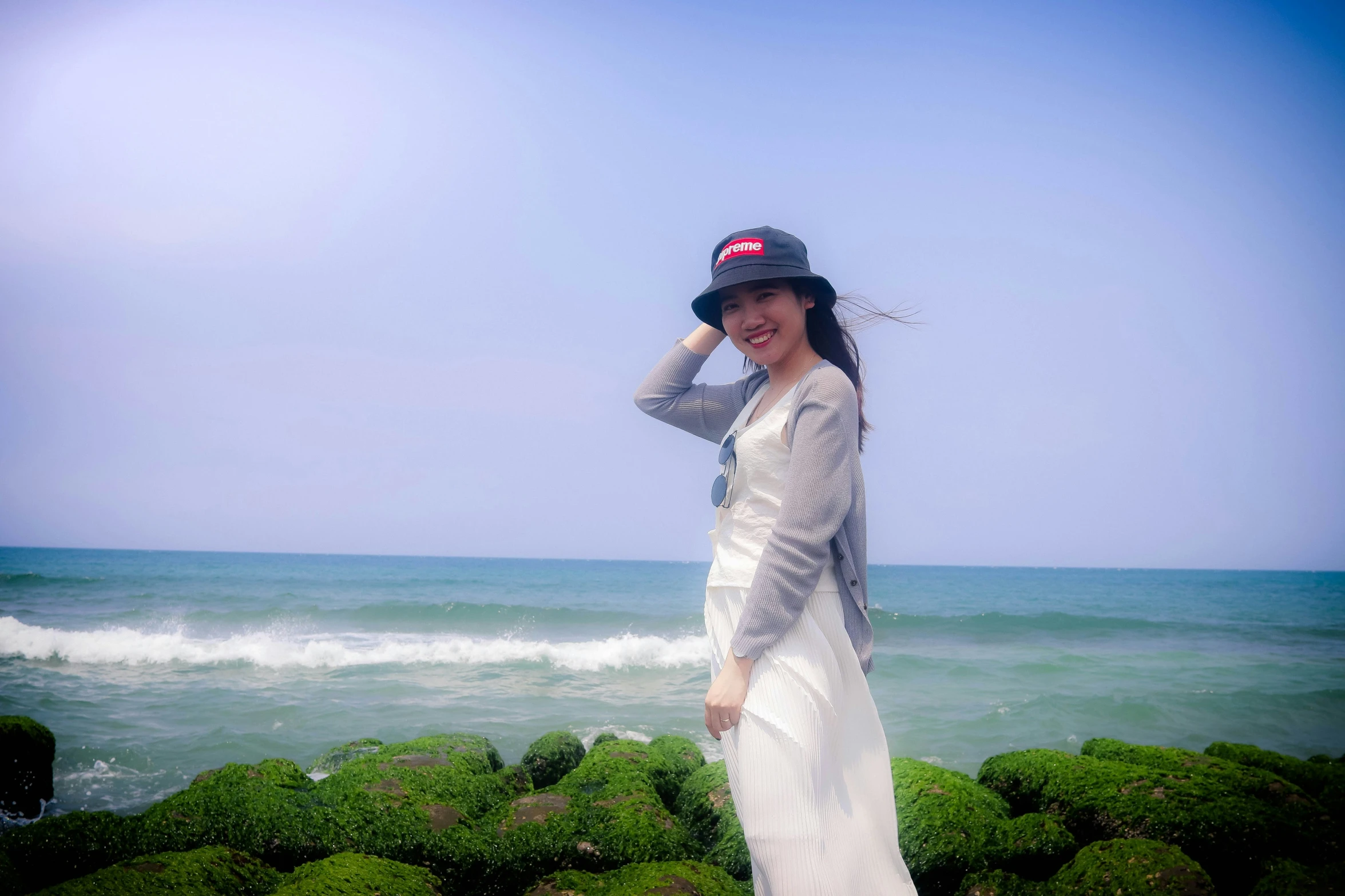 a woman standing in front of a large green grass covered beach