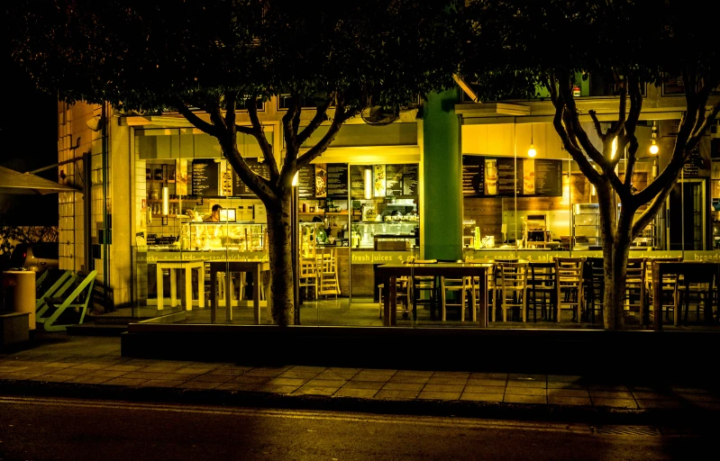 a restaurant is lit up at night, with lights in the windows