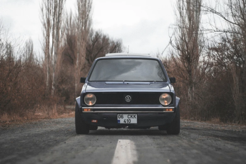 an old black car on a dusty road