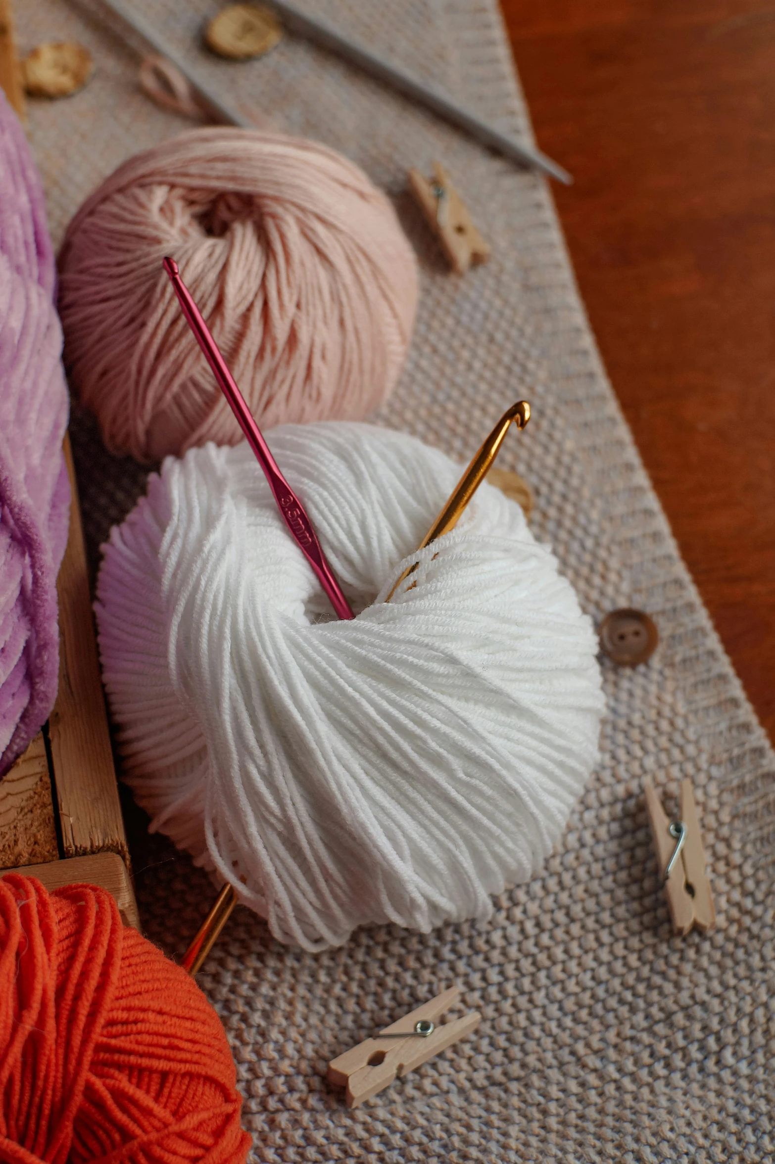 there are yarns, crochet hooks and needles on the table