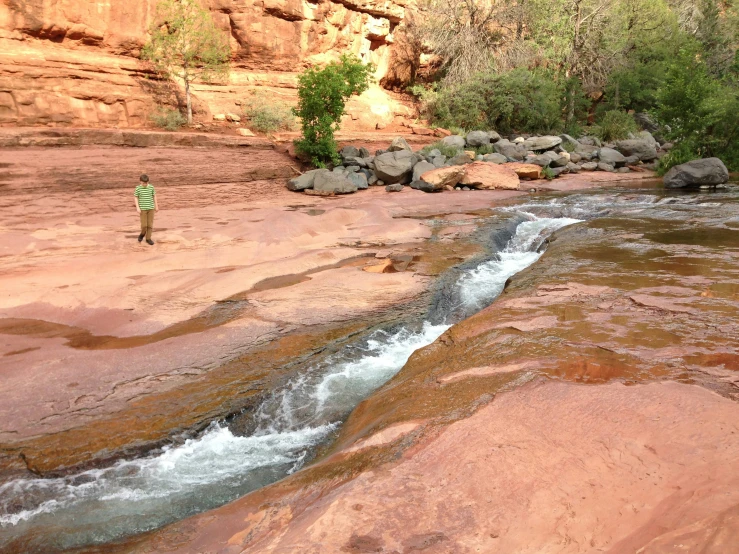 a small stream running through red rocks in the desert