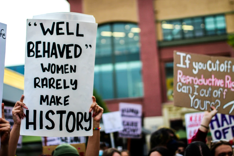 many women protesting with signs in front of a building