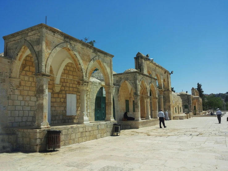 men walking past an old wall on a road