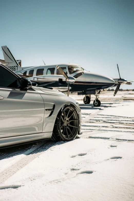 a silver car parked next to an airplane