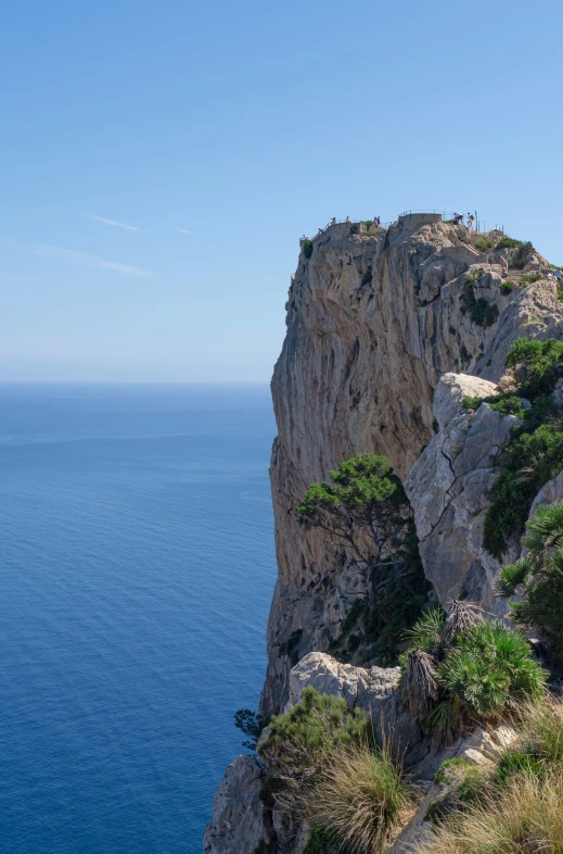 a steep cliff with vegetation and water below