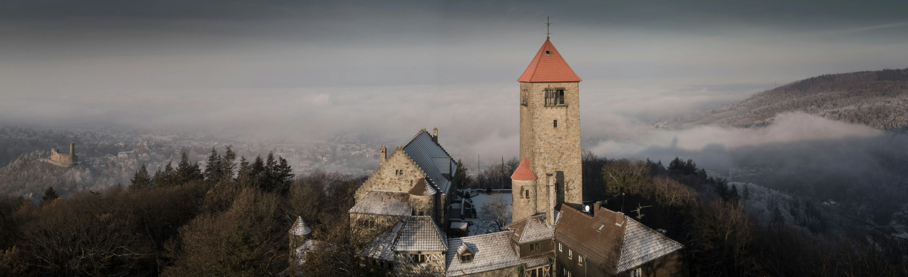 a very tall church tower towering over a forest filled with fog