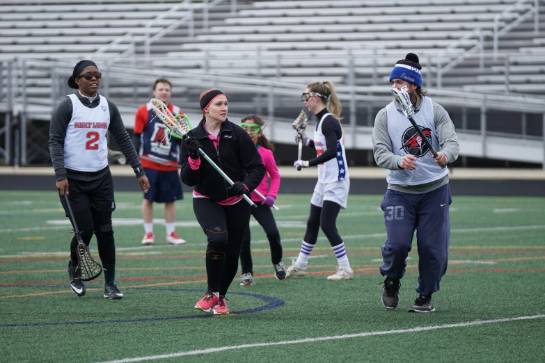 girls are playing field hockey while wearing black jackets