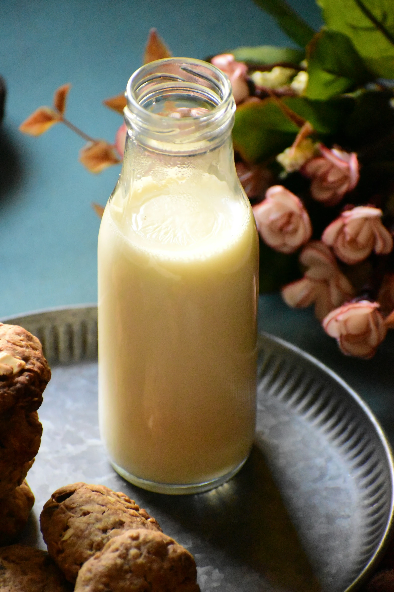 cookies with a jar of milk are in front of a bouquet of roses