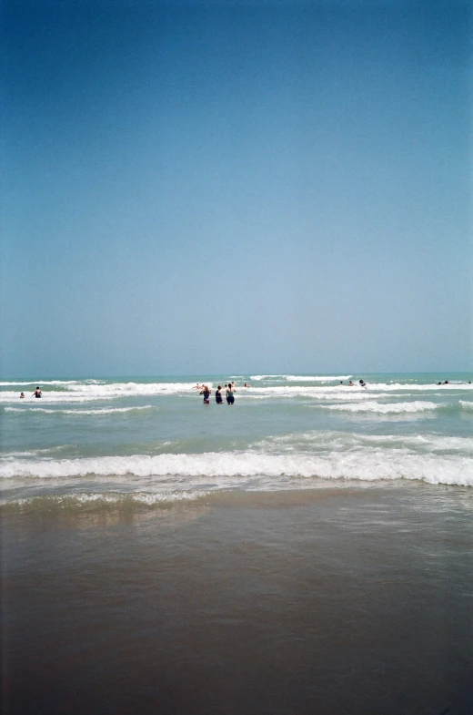 group of people wading in the ocean on the beach