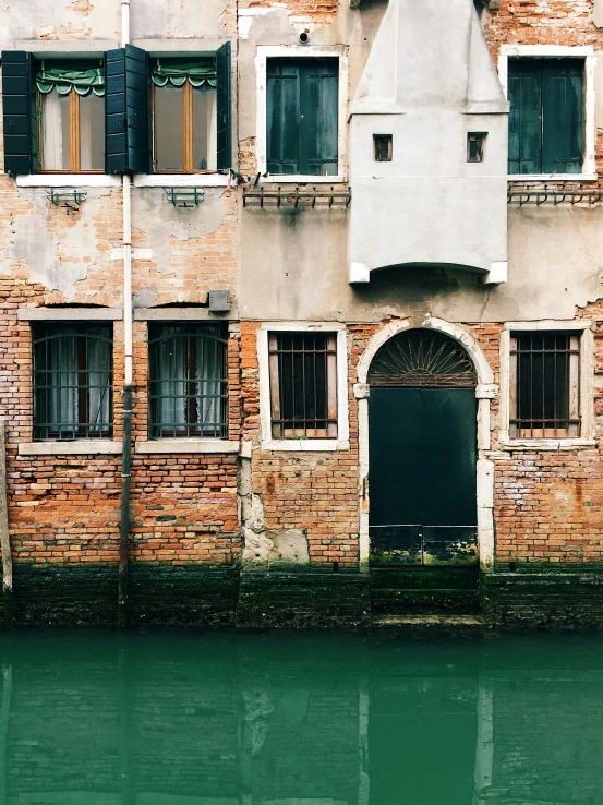 an old building with lots of windows and a door by the water