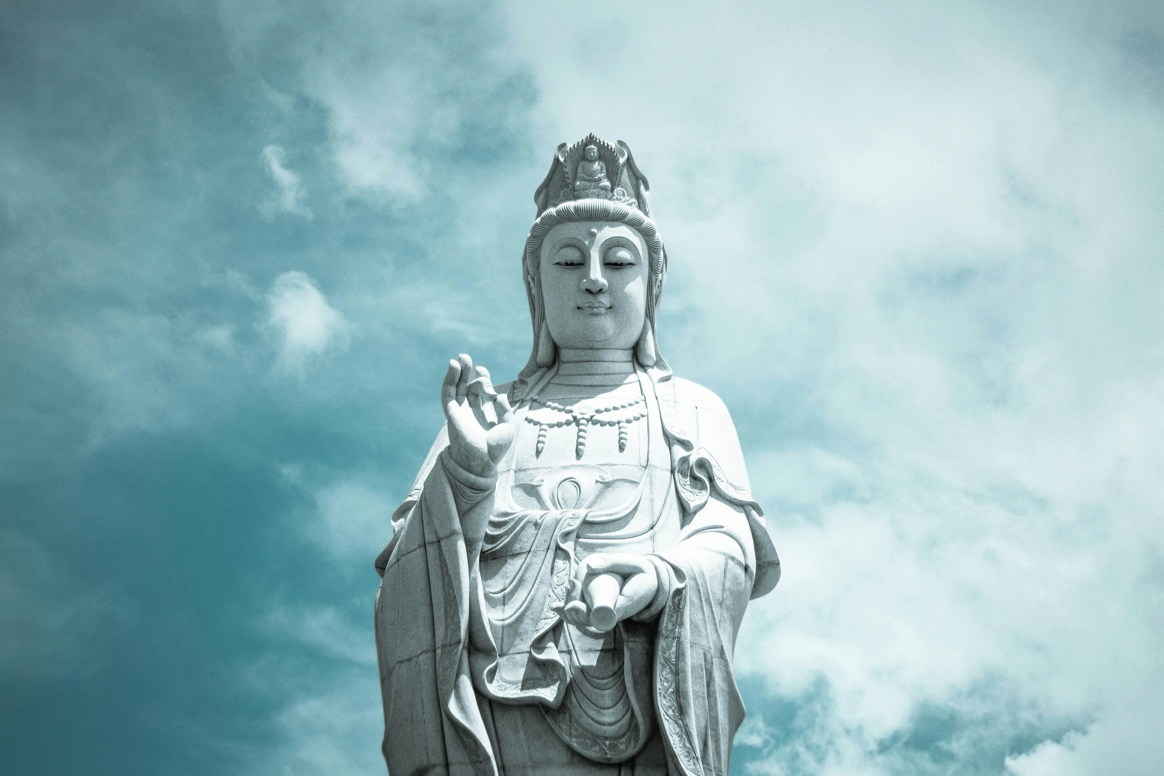 a white statue is in front of a cloudy sky