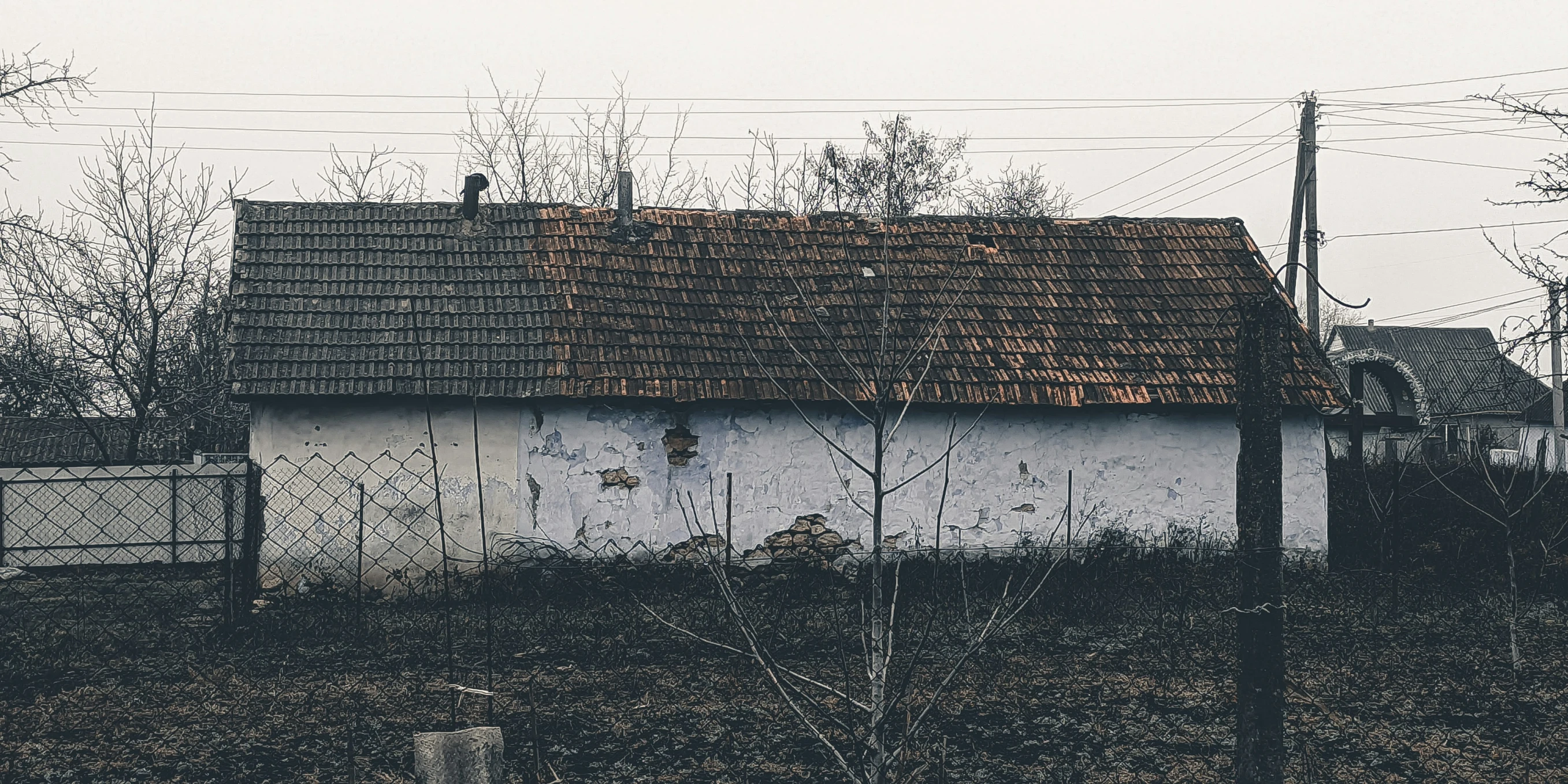 a fence and house in the background surrounded by power lines